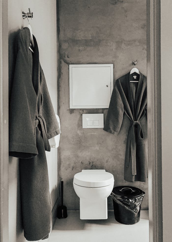 Modern bathroom featuring bathrobes and a toilet in a minimalist style.