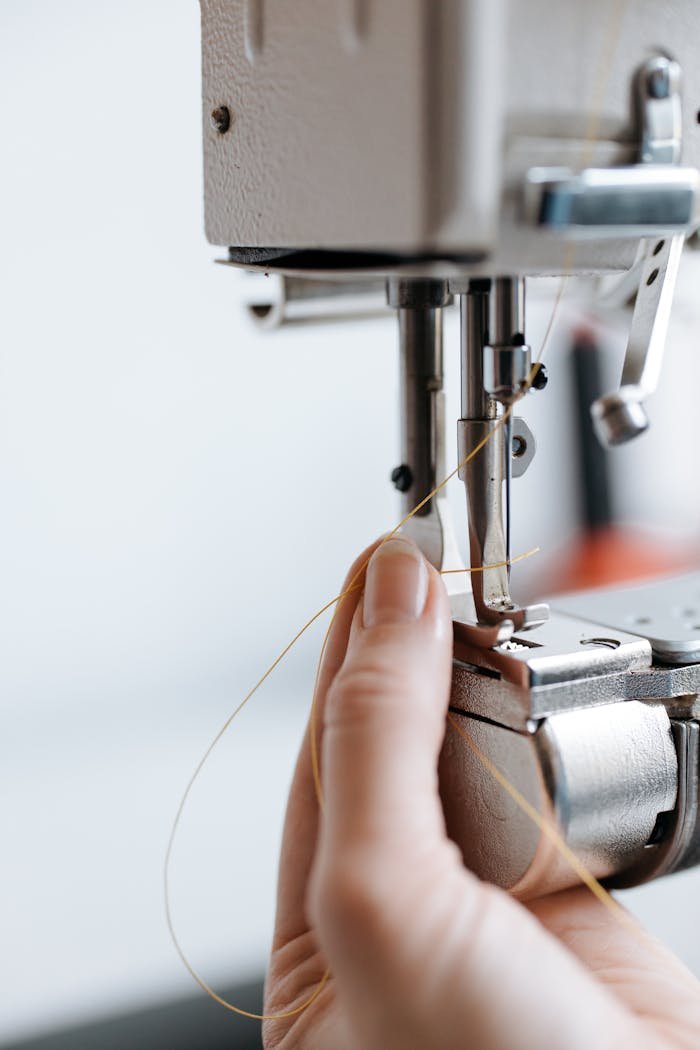 Detailed view of a sewing machine needle threading process. Perfect for textile industry visuals.